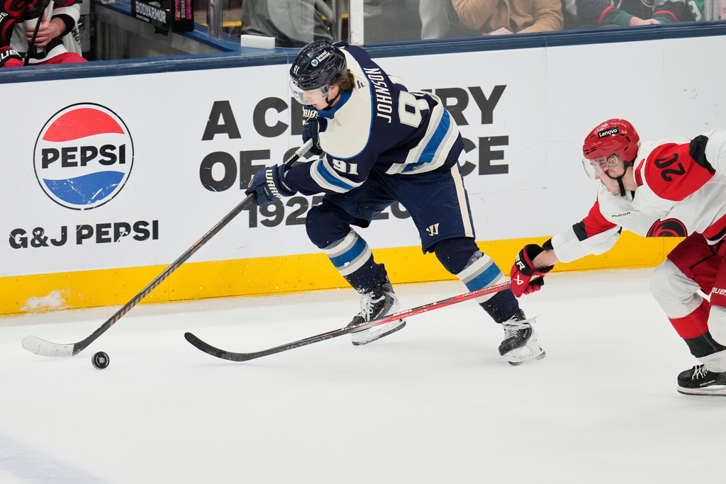 Columbus Blue Jackets' Kent Johnson (91) takes the puck past Carolina Hurricanes' Sebastian Aho (20) in the second period of an NHL hockey game in Columbus, Tuesday, March 17, 2026. (AP Photo/Sue Ogrocki)