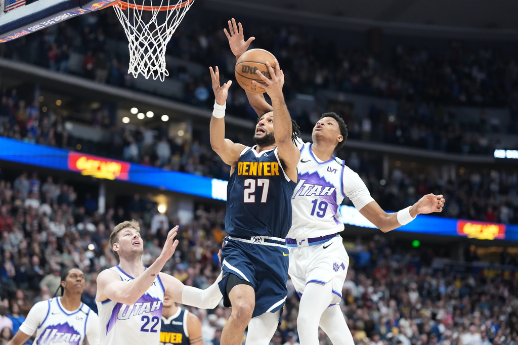 Denver Nuggets guard Jamal Murray, center, is fouled by Utah Jazz forward Ace Bailey, right, as center Kyle Filipowski defends in the first half of an NBA basketball game Friday, March 27, 2026, in Denver. (AP Photo/David Zalubowski)