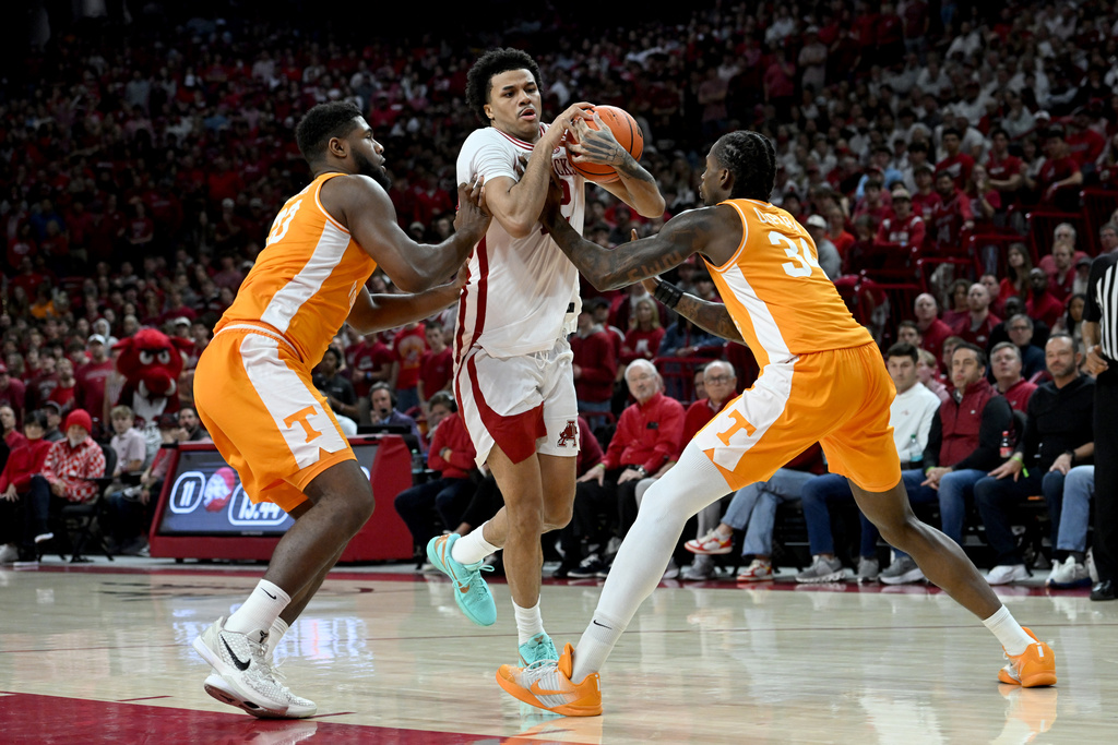 Arkansas forward Malique Ewin, center, tries to drive past Tennessee defenders Jaylen Carey, left, and Troy Henderson, right, during the first half of an NCAA college basketball game Saturday, Jan. 3, 2026, in Fayetteville, Ark. (AP Photo/Michael Woods)