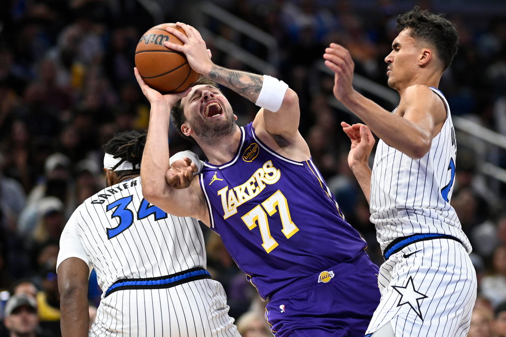 Los Angeles Lakers guard Luka Doncic (77) is fouled by Orlando Magic center Wendell Carter Jr. (34) as Magic forward Tristan da Silva, right, helps defend during the first half of an NBA basketball game, Saturday, March 21, 2026, in Orlando, Fla. (AP Photo/Phelan M. Ebenhack)