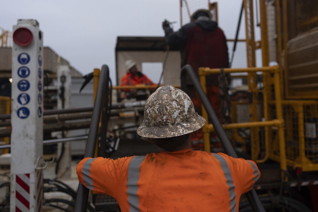 Grease-covered Expedition 501 drilling team member Chris Redding works on the wireline core drilling rig aboard the Liftboat Robert platform, in the North Atlantic, Sunday, July 20, 2025. (AP Photo/Carolyn Kaster)