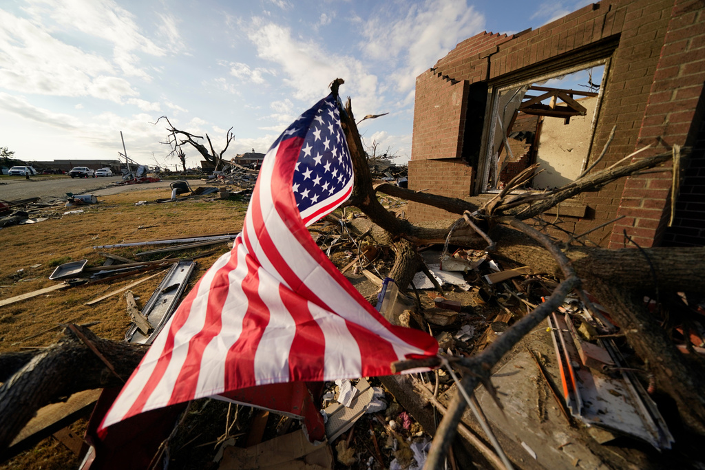 FILE - An American flag flies amidst debris of destroyed homes, in the aftermath of tornadoes that tore through the region, in Mayfield, Ky., Dec. 14, 2021. (AP Photo/Gerald Herbert, File)