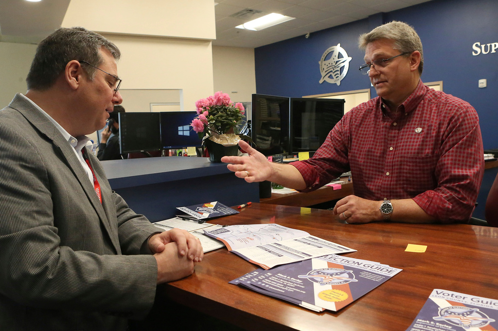 FILE - Mark Earley, Leon County supervisor of elections, right, shows Don Palmer, of the federal election assistance commission, the sample ballot for the Tuesday primary, March 12, 2020 in Tallahassee, Fla. (AP Photo/Steve Cannon, File)