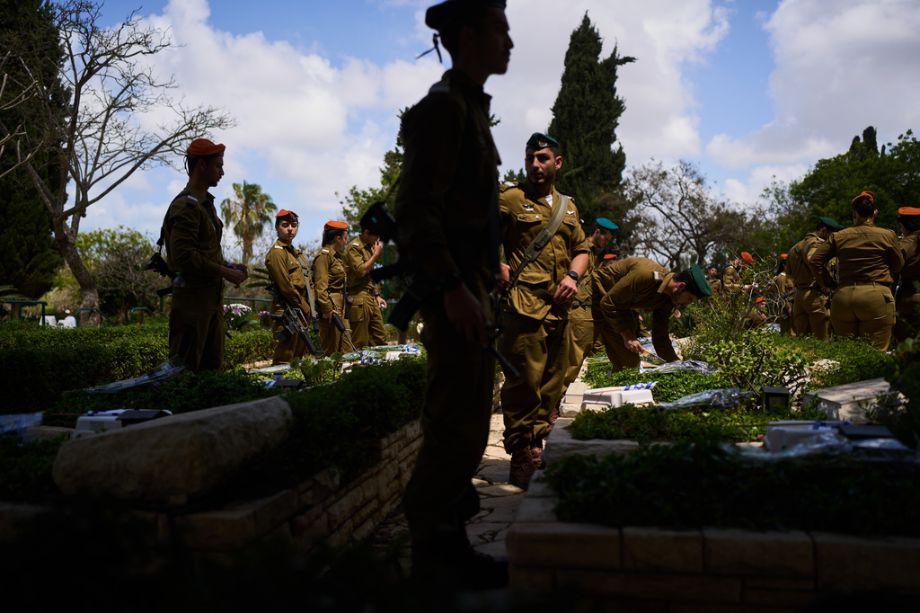 Israeli soldiers place flags and flowers on graves at a military cemetery ahead of the annual Memorial Day honoring fallen soldiers and victims of nationalistic attacks in Tel Aviv, Israel, Monday, April 20, 2026. (AP Photo/Oded Balilty)