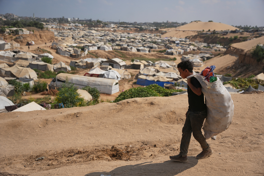 A Palestinian boy leaves a garbage dump after collecting combustible materials to use as fuel for cooking due to a shortage of cooking gas, in Deir al-Balah, central Gaza Strip, Saturday, Aug. 22, 2026. (AP Photo/Abdel Kareem Hana)