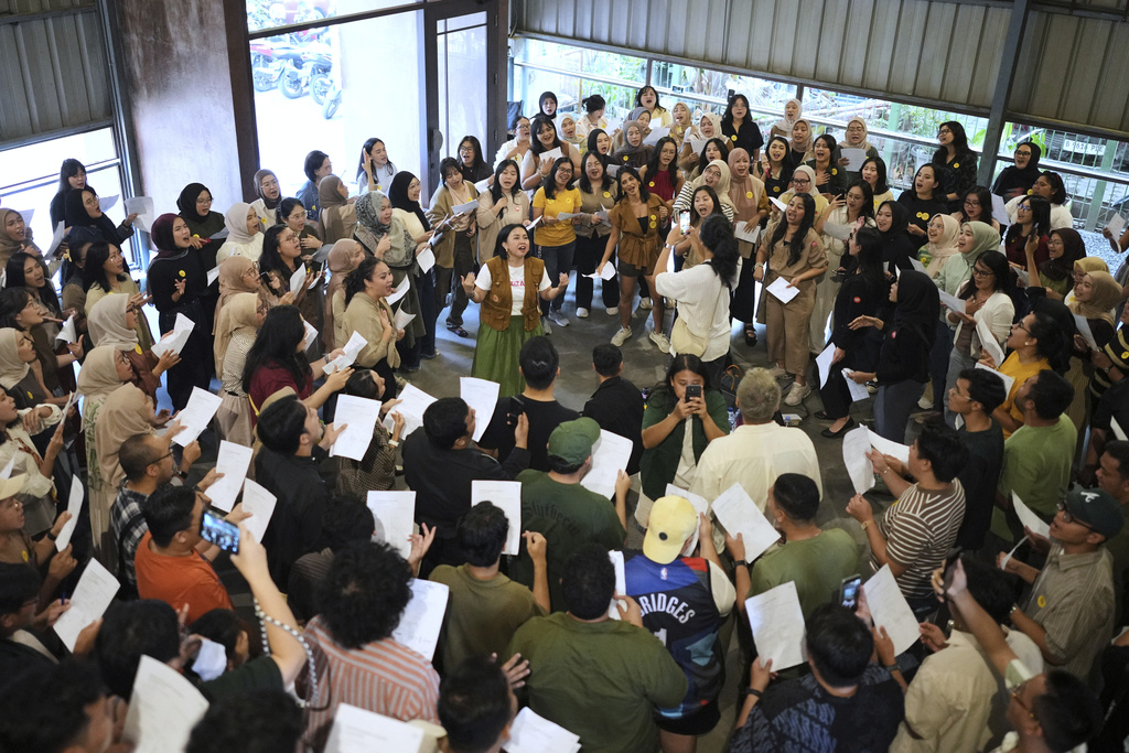 Meda Kawu, center, co-founder of Nyanyi Bareng Jakarta, or Singing Together Jakarta, leads participants during a gathering in Jakarta, Indonesia, Saturday, July 19, 2025. (AP Photo/Dita Alangkara)