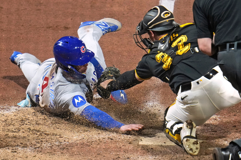 Chicago Cubs' Pete Crow-Armstrong, left, gets his hand on home plate before Pittsburgh Pirates catcher Henry Davis (32) can apply a tag to score on a fielder's choice hit into by Alex Bregman off pitcher Yohan Ramírez during the ninth inning of a baseball game in Pittsburgh, Thursday, May 28, 2026. (AP Photo/Gene J. Puskar)