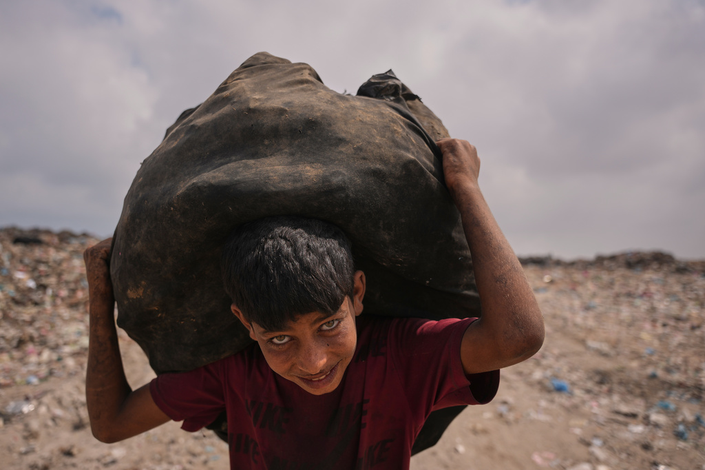 Omar Ghabin, 14, looks at the camera as he carries a bag of items he collected from the landfill in Deir al-Balah, central Gaza Strip, Thursday, July 23, 2026. (AP Photo/Abdel Kareem Hana)