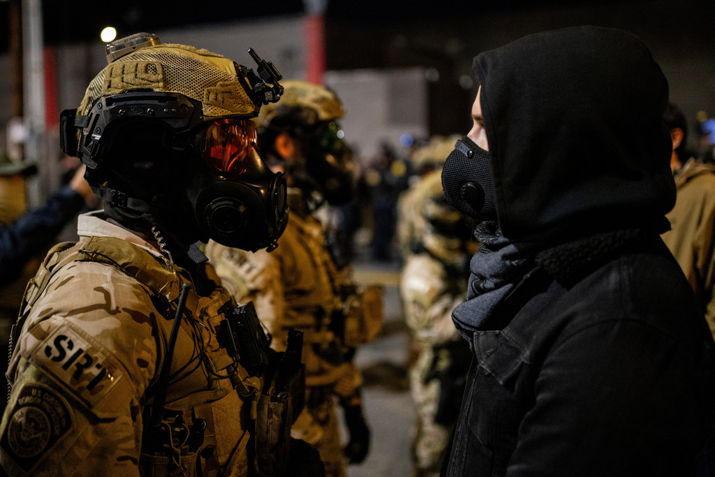 An officer with the Department of Homeland Security Special Response Team (SRT) stands against a protester outside a United States Immigration and Customs Enforcement (ICE) facility as protests against the Trump administration continue in Portland, Ore., Monday, Oct. 6, 2025. (Stephen Lam/San Francisco Chronicle via AP)