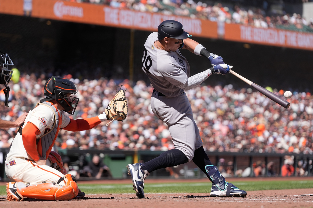 New York Yankees' Aaron Judge, right, hits a two-run home run next to San Francisco Giants catcher Patrick Bailey during the sixth inning of a baseball game in San Francisco, Friday, March 27, 2026. (AP Photo/Jeff Chiu)