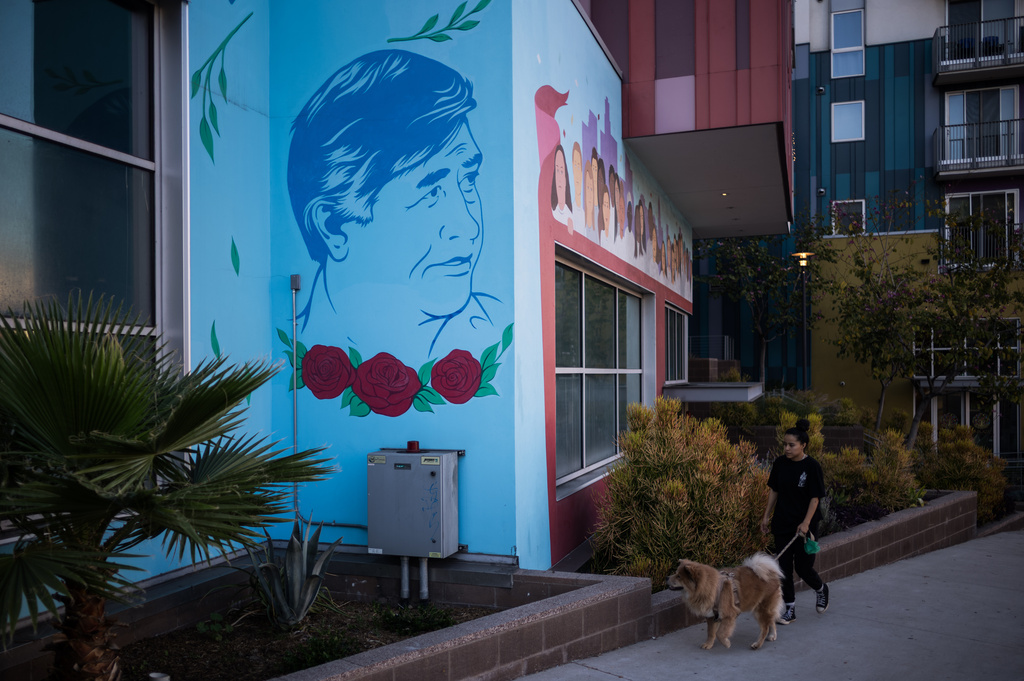 A woman and her dog walk past a mural of Cesar Chavez outside the Cesar Chavez Foundation office in Los Angeles, Wednesday, March 18, 2026. (AP Photo/Jae C. Hong)