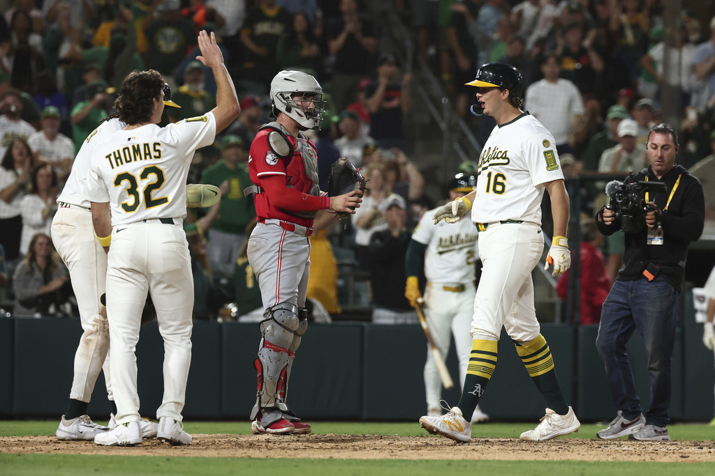 Athletics' Nick Kurtz, right, celebrates as he crosses home plate after hitting a grand slam during the eighth inning of a baseball game against the Cincinnati Reds Saturday, Sept. 13, 2025, in West Sacramento, Calif. (AP Photo/Sara Nevis)