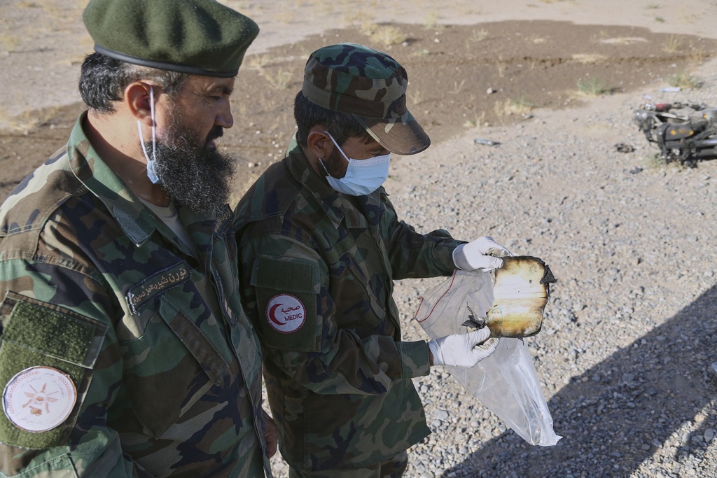 A medic from the Taliban army collects items at the site where a burned-out bus collided with a truck and a motorbike Tuesday evening, causing a massive fire and killing at least 70 people, including children, most of them Afghans returning from Iran, in western Herat province, Afghanistan, Wednesday, Aug. 20, 2025. (AP Photo/Omid Haqjoo)
