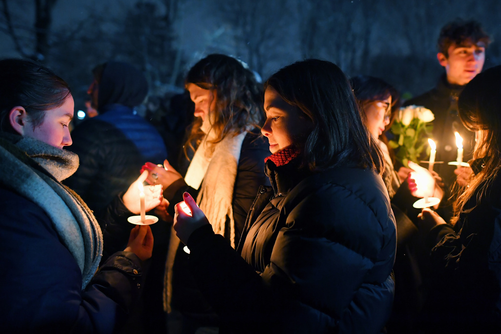 FILE - People hold candles during a vigil, Dec. 14, 2025, in Providence, R.I., for the victims of Saturday's shooting on the campus of Brown University. (AP Photo/Steven Senne, File)