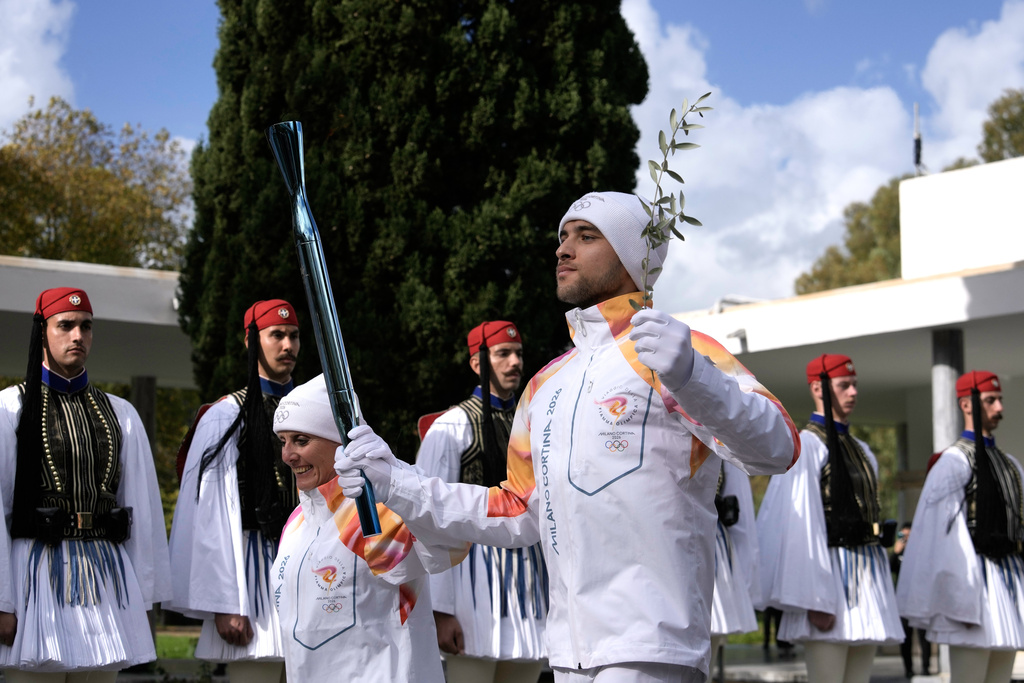 Greek rower Petros Gaidatzis, right, and former Italy's Cross Country skier Stefania Belmondo start the torch relay after the ceremony of the flame lighting for the Milan Cortina 2026 Winter Olympics, at the archaeological museum of Olympia, Greece, Wednesday, Nov. 26, 2025. (AP Photo/Petros Giannakouris)