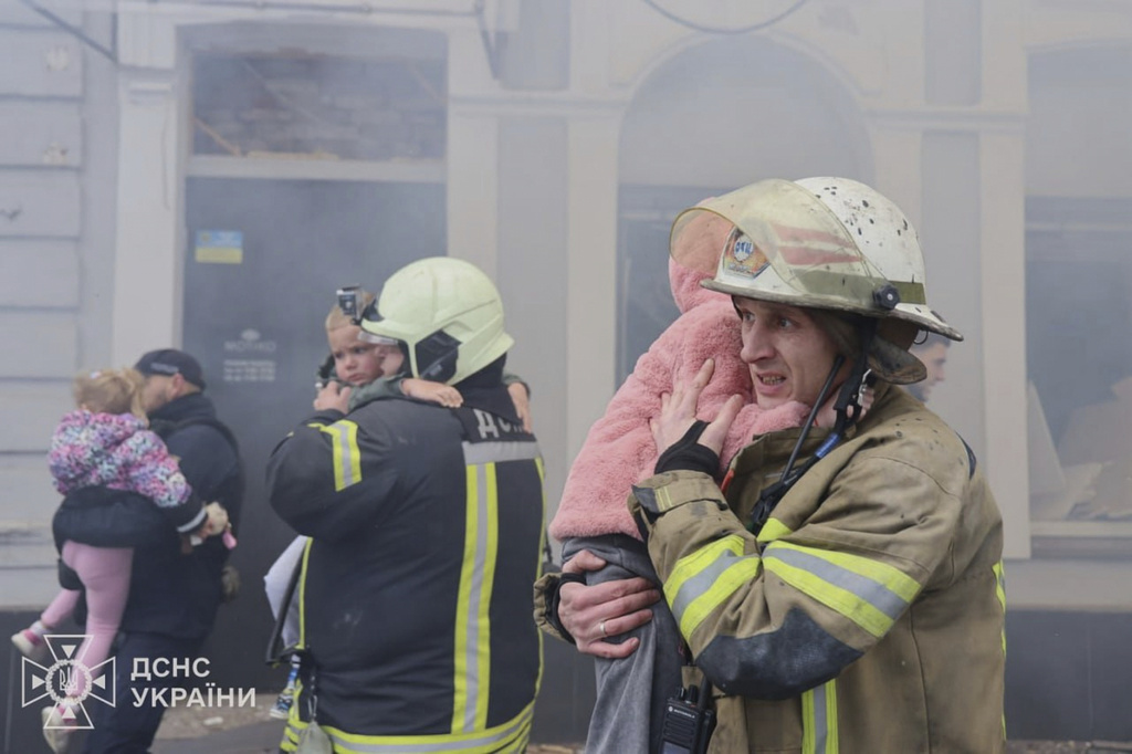In this photo provided by the Ukrainian Emergency Service, rescuers evacuate children after Russian drones hit a city kindergarten during an attack in Kharkiv, Ukraine, Wednesday, Oct. 22, 2025. (Ukrainian Emergency Service via AP)