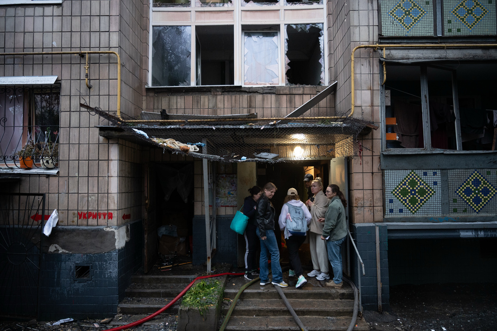 Local residents gather near the entrance to a damaged residential building following an overnight Russian attack in Kyiv, Ukraine, Monday, June 15, 2026. (AP Photo/Danylo Antoniuk)