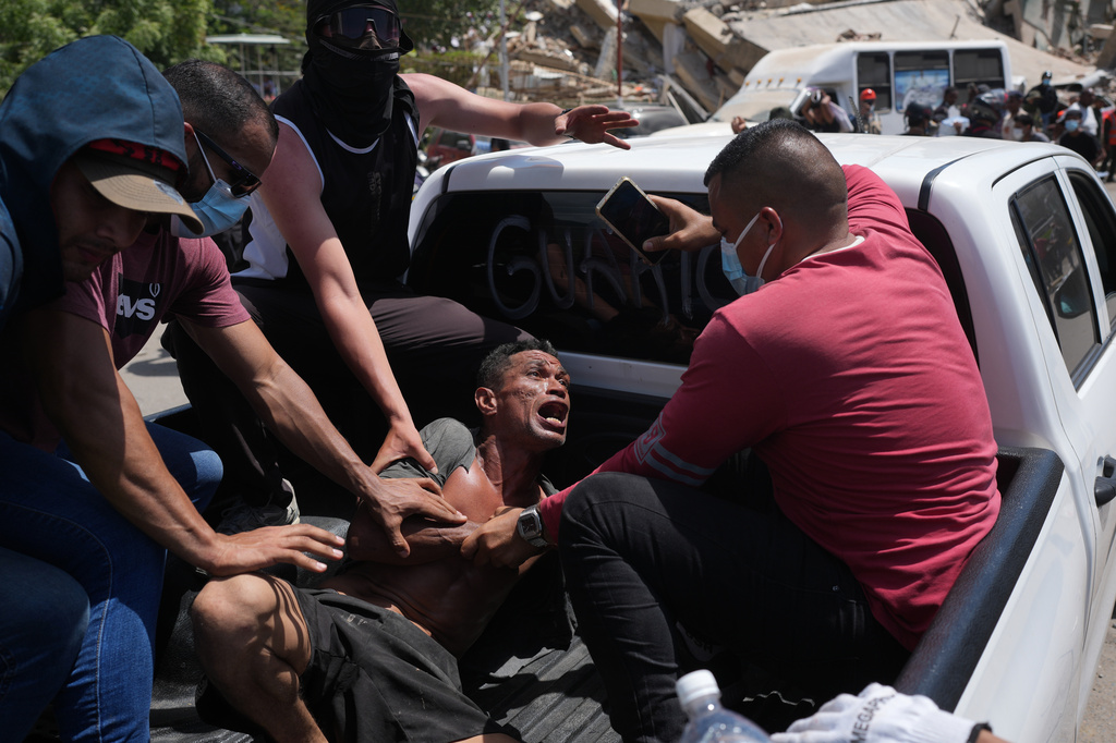 Residents transport a man rescued from the rubble three days after earthquakes struck, in La Guaira, Venezuela, Saturday, June 27, 2026. (AP Photo/FMatias Delacroix)