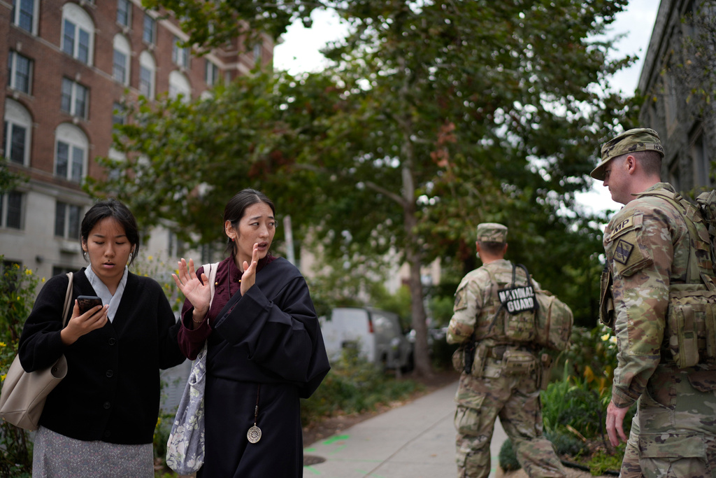 Namkyi, right, a Tibetan former political prisoner who was arrested at 15 for protesting Chinese rule, walks past National Guard troops on patrol with Tsejin Khando, with the International Campaign for Tibet, to a meeting, Oct. 7, 2025, in Washington. (AP Photo/David Goldman)