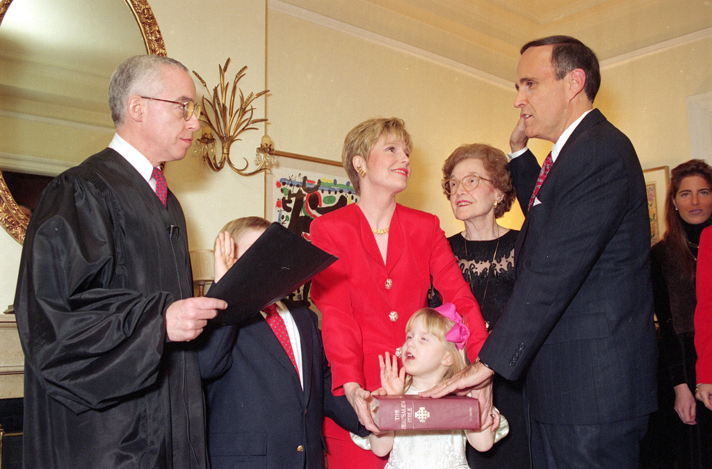 FILE - Republican Rudolph Giuliani, right, is symbolically sworn-in as New York City Mayor by U.S. District Court Judge Michael B. Mukasey, left, during a private ceremony in New York, Friday, Dec. 31, 1993. Giuliani's wife Donna Hanover, center, stands with their children Andrew, 7, and Caroline, 4 and Giuliani's mother Helen looks on. (AP Photo/Ed Bailey, File)