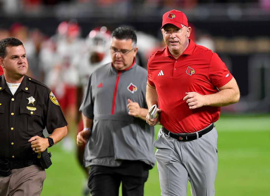 Louisville head coach Jeff Brohm, right, runs off the field after his team defeated Miami in an NCAA college football game, Friday, Oct. 17, 2025, in Miami Gardens, Fla. (AP Photo/Michael Laughlin)