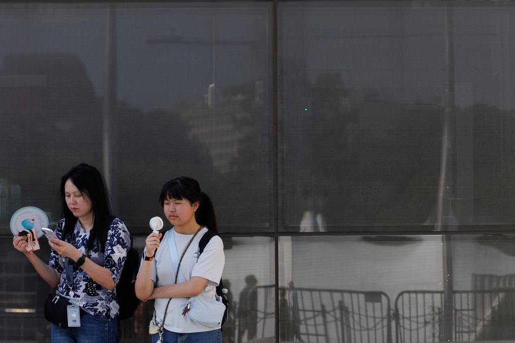 FILE - Visitors use fans as as they wait to enter the Washington Monument, July 1, 2026, in Washington. (AP Photo/Tom Brenner, File)