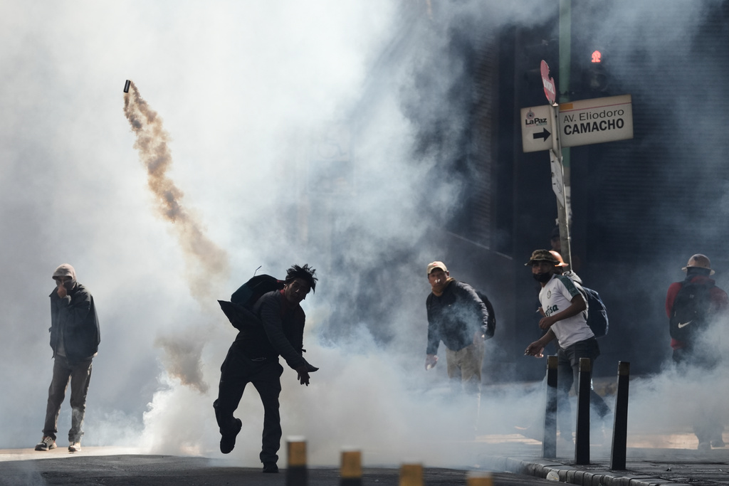FILE - A protester hurls back a canister in clashes with police during a Workers' Union protest against fuel subsidy cuts in El Alto, Bolivia, Jan. 5, 2026. (AP Photo/Freddy Barragan, File)