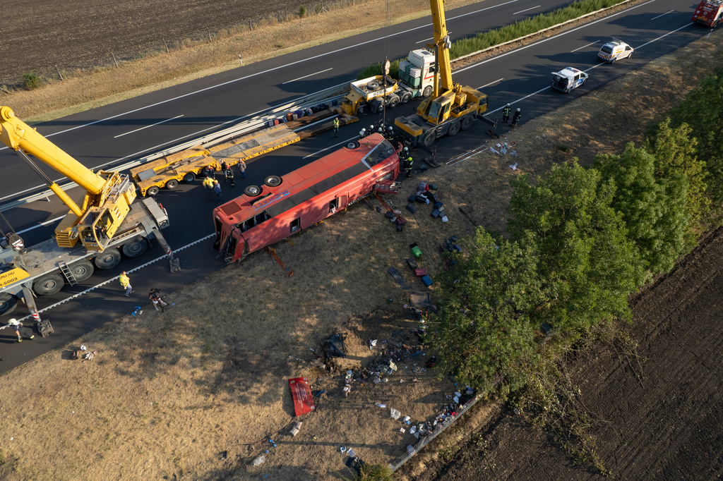 An aerial photo taken by drone shows the emergency services as they attend the scene after a passenger bus went off the road and overturned in a ditch along a highway between Mezokeresztes and Mezonagymihaly in Hungary, Sunday, Aug. 16, 2026. (Zoltan Mathe/MTI via AP)