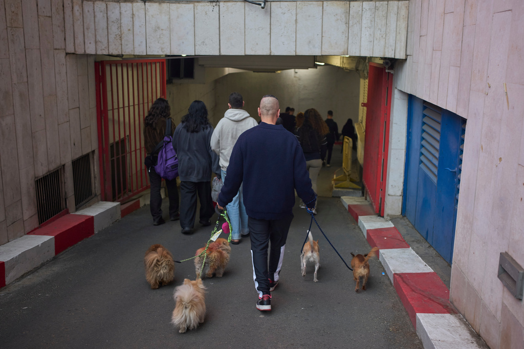 People take shelter in an underground parking garage as air raid sirens warn of incoming missiles launched by Iran toward Tel Aviv, Israel, Friday, March 13, 2026. (AP Photo/Ohad Zwigenberg)