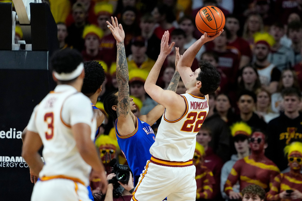 Iowa State forward Milan Momcilovic (22) looks for a basket under the hoop as Kansas guard Tre White (3) defends during the first half of an NCAA college basketball game, Saturday, Feb. 14, 2026, in Ames, Iowa. (AP Photo/Matthew Putney)