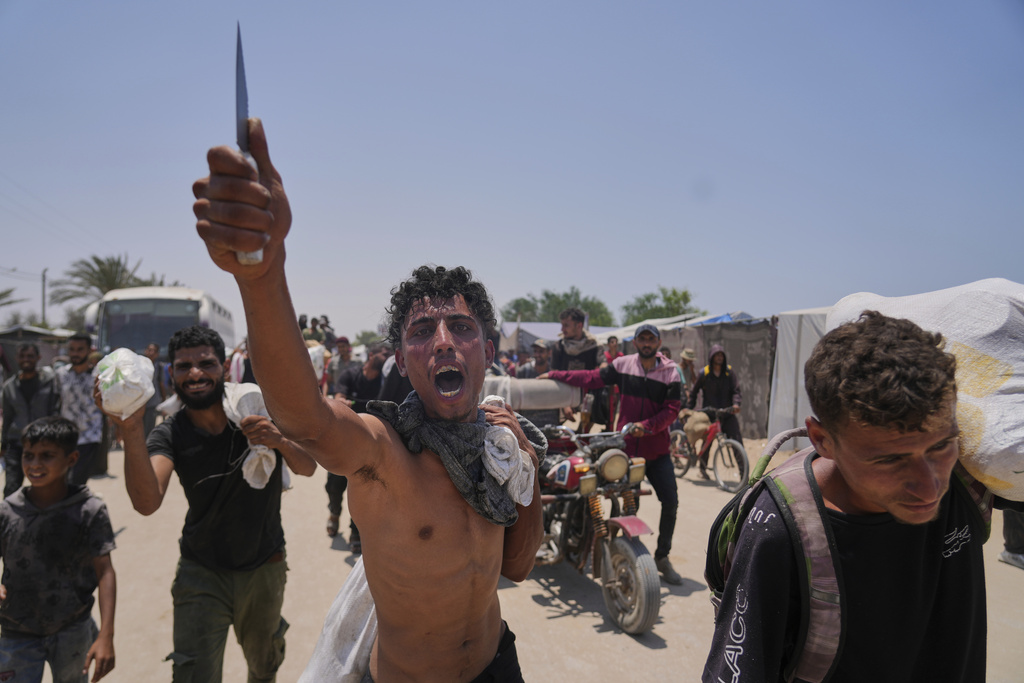 A Palestinian shouts to the camera in Arabic, "We get food with the taste of death and blood," as he carries a bag containing food and humanitarian aid packages delivered by the Gaza Humanitarian Foundation, a U.S.-backed organization, in Rafah, southern Gaza Strip, June 10, 2025. (AP Photo/Abdel Kareem Hana)