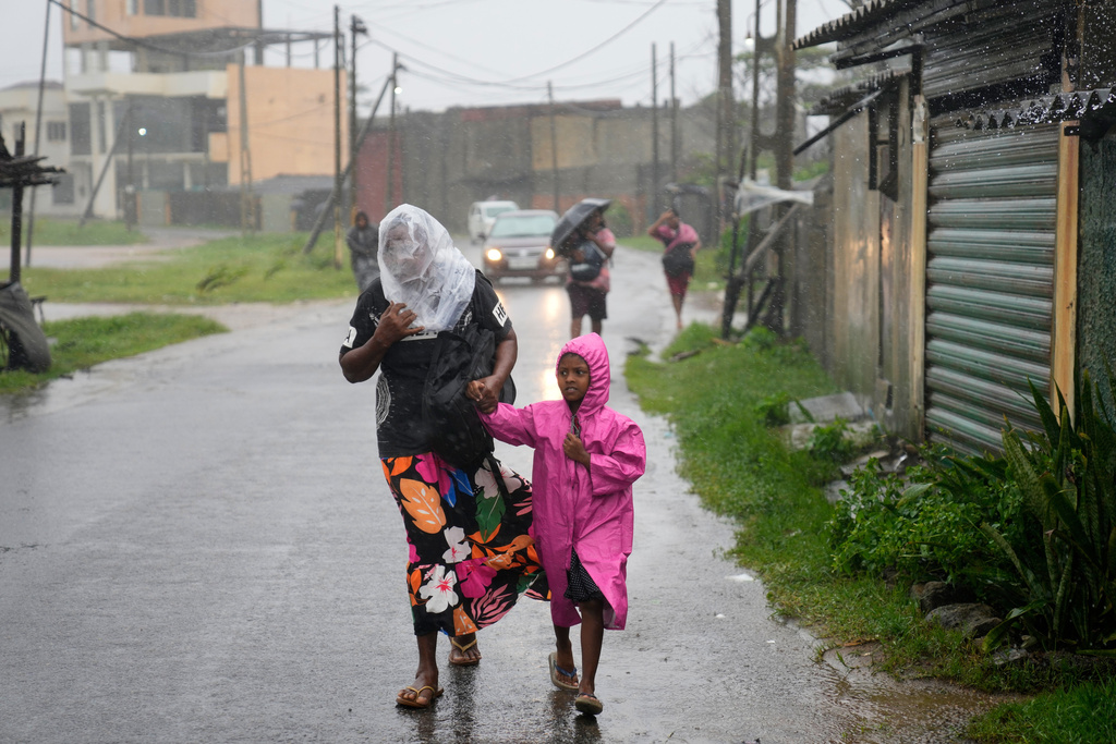 A woman and child walk under a downpour in Colombo, Sri Lanka, Friday, Nov. 28, 2025. (AP Photo/Eranga Jayawardena)