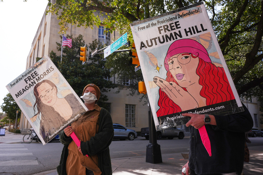 People hold signs across the street from the Eldon B. Mahon U.S. Courthouse during a trial for nine people connected to a 2025 shooting outside an ICE detention facility Tuesday, Feb. 24, 2026, in Fort Worth, Texas. (AP Photo/LM Otero)