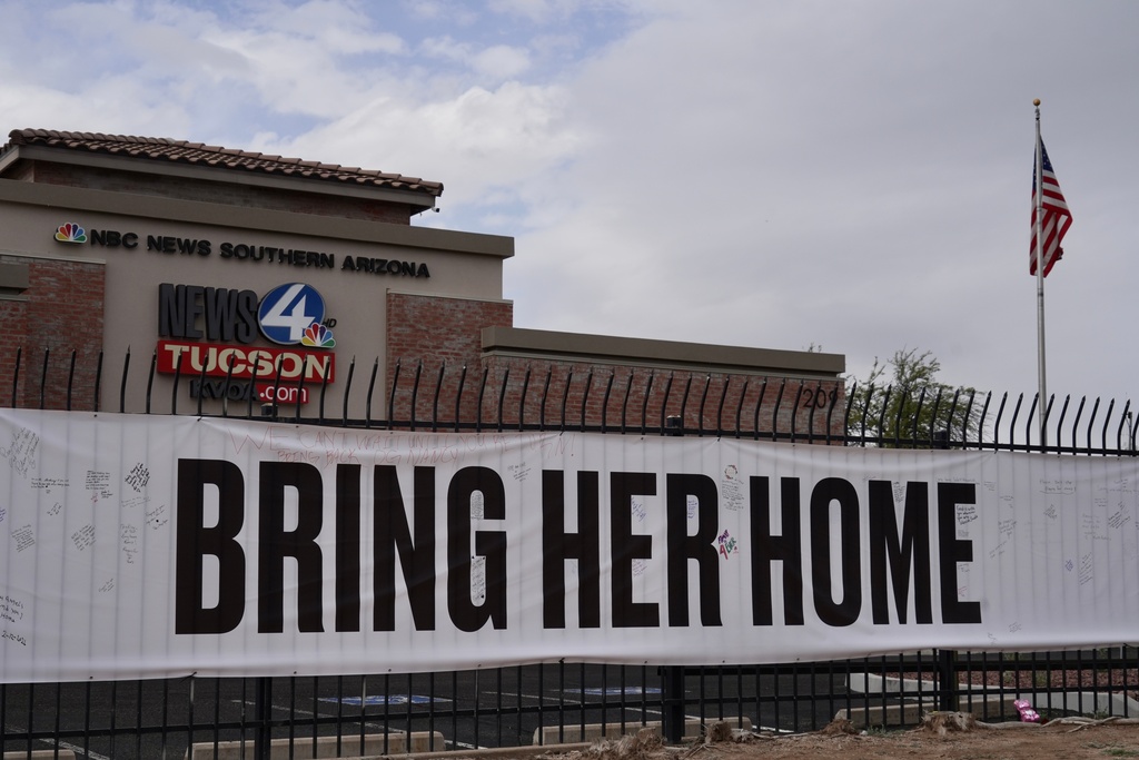 A banner reading "Bring her home" on a fence outside of the KVOA news station in Tucson, Ariz., on Friday, Feb. 13, 2026. (AP Photo/Ty ONeil)