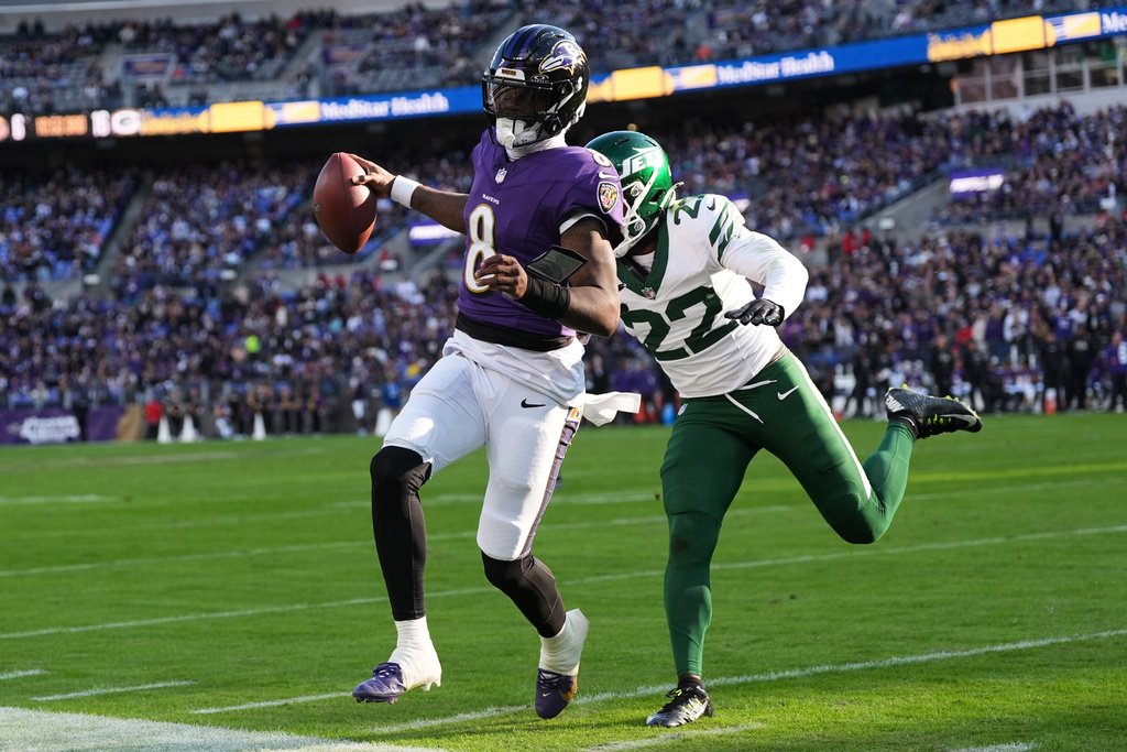 Baltimore Ravens quarterback Lamar Jackson (8) runs as New York Jets safety Tony Adams (22) defends during the second half of an NFL football game, Sunday, Nov. 23, 2025, in Baltimore. (AP Photo/Stephanie Scarbrough)
