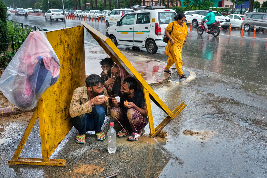 Laborers drink tea, sitting under tin shade panels to shelter themselves from the rain during roadwork, in New Delhi, India, Monday, Sept. 1, 2025. (AP Photo/Manish Swarup)