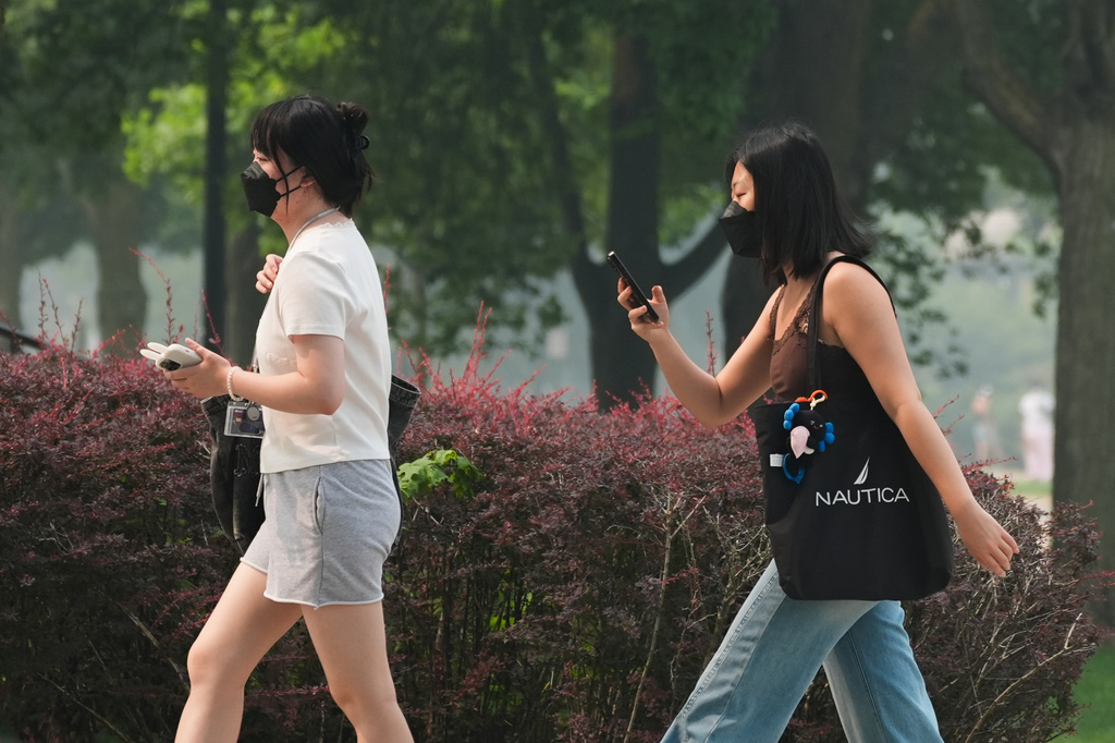 People wear masks as they walk on the street during poor air quality due to dense smoke from Canadian wildfires in Evanston, Ill., Thursday, July 16, 2026. (AP Photo/Nam Y. Huh)