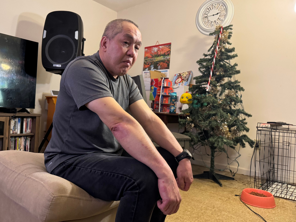 FILE - Chongly "Scott" Thao, a U.S. citizen, sits for a photo at his home Jan. 19, 2026, in St. Paul, Minn., the day after federal agents broke open his door and detained him without a warrant. (AP Photo/Jack Brook, file)
