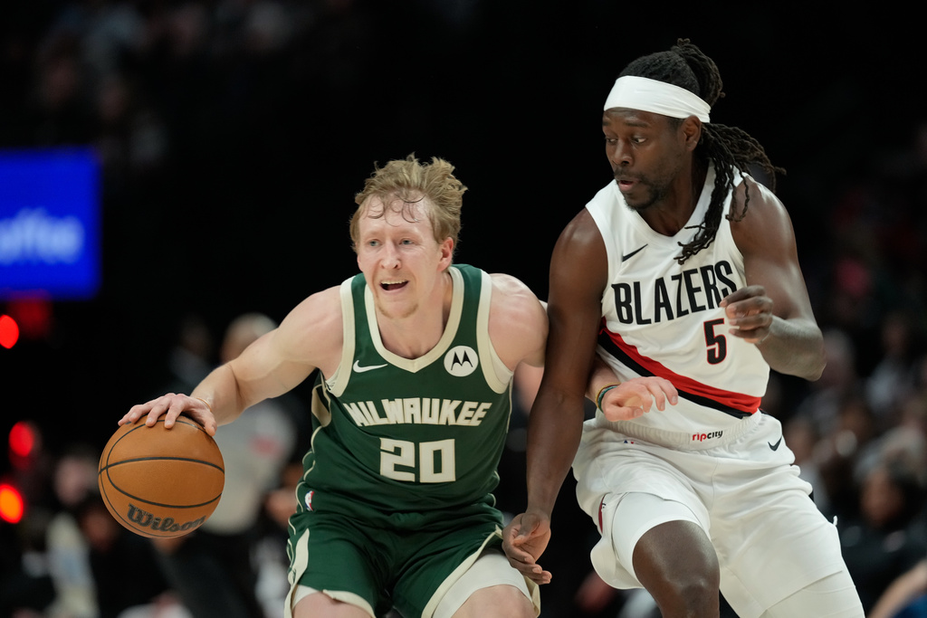Milwaukee Bucks guard AJ Green (20) tries to get past Portland Trail Blazers guard Jrue Holiday (5) during the first half of an NBA basketball game Wednesday, March 25, 2026, in Portland, Ore. (AP Photo/Jenny Kane)