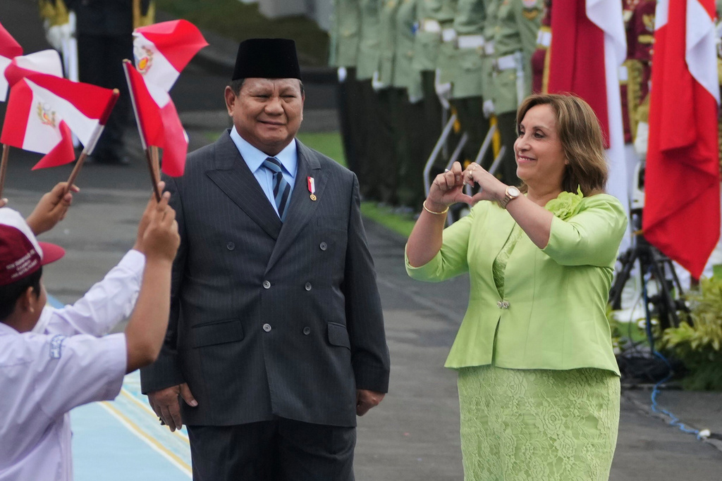Peruvian President Dina Boluarte, right, gives a love symbol at children waving Indonesian and Peruvian flags as his Indonesian counterpart Prabowo Subianto looks on during a welcoming ceremony prior to their meeting at Merdeka Palace in Jakarta, Indonesia, Monday, Aug. 11, 2025. (AP Photo/Achmad Ibrahim)