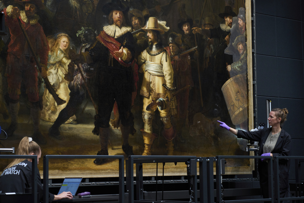 An art restorer points at the image of a dog in Rembrandt's Night Watch at Amsterdam's Rijksmuseum, Netherlands, Tuesday, Sept. 23, 2025. (AP Photo/Peter Dejong)