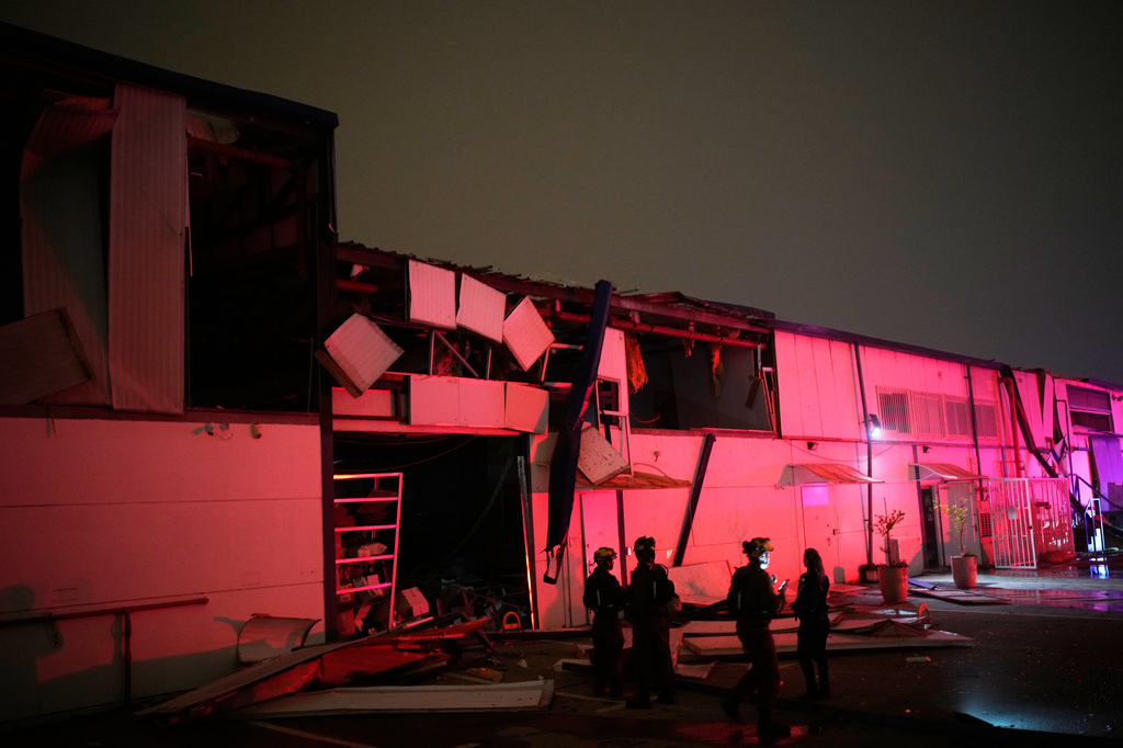 Israeli security forces and rescue teams inspect a site struck by an Iranian missile in Petah Tikva, Israel,Thursday, April 2, 2026. (AP Photo/Ohad Zwigenberg)