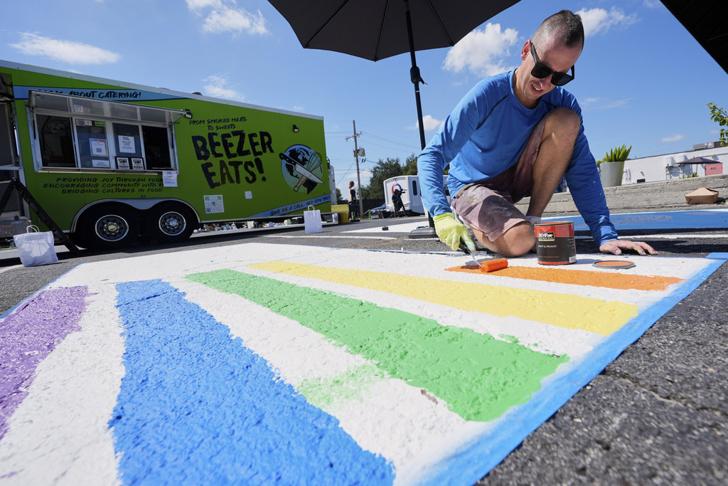 Paul Silva paints a parking space at a local restaurant to support the LBGTQ+ community and to protest state mandates on crosswalk art Monday, Sept. 15, 2025, in Orlando, Fla. (AP Photo/John Raoux)