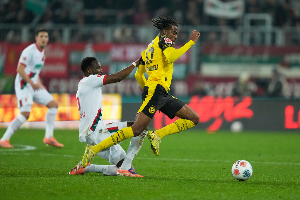 Augsburg's Chrislain Matsima, left, challenges for the ball with Dortmund's Carney Chukwuemeka during the Bundesliga soccer match between FC Augsburg and Borussia Dortmund in Augsburg, Germany, Friday, Oct. 31, 2025. (AP Photo/Matthias Schrader)