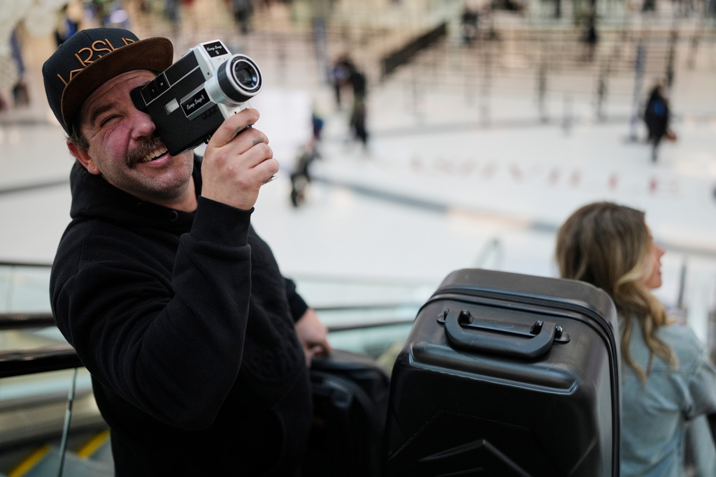 Jordan Heid uses an old film camera as he arrives for his flight at the Nashville International Airport, Tuesday, Nov. 25, 2025, in Nashville, Tenn. (AP Photo/George Walker IV)