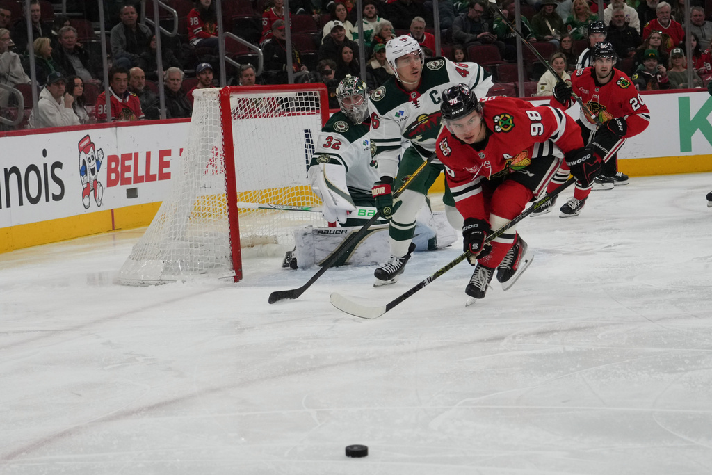 Chicago Blackhawks center Connor Bedard (98) and Minnesota Wild defenseman Jared Spurgeon (46) skate for the puck during the first period of an NHL hockey game, Tuesday, March, 17, 2026, in Chicago. (AP Photo/David Banks)