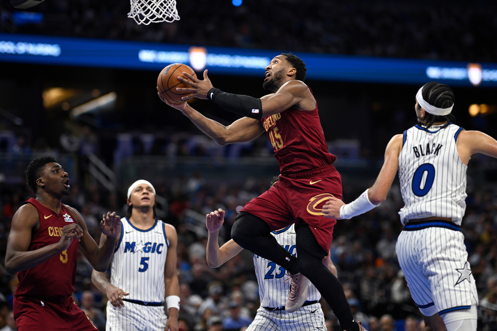 Cleveland Cavaliers guard Donovan Mitchell (45) goes up to shoot between Orlando Magic forward Tristan da Silva (23) and guard Anthony Black (0) during the second half of an NBA basketball game, Saturday, Jan. 24, 2026, in Orlando, Fla. (AP Photo/Phelan M. Ebenhack)