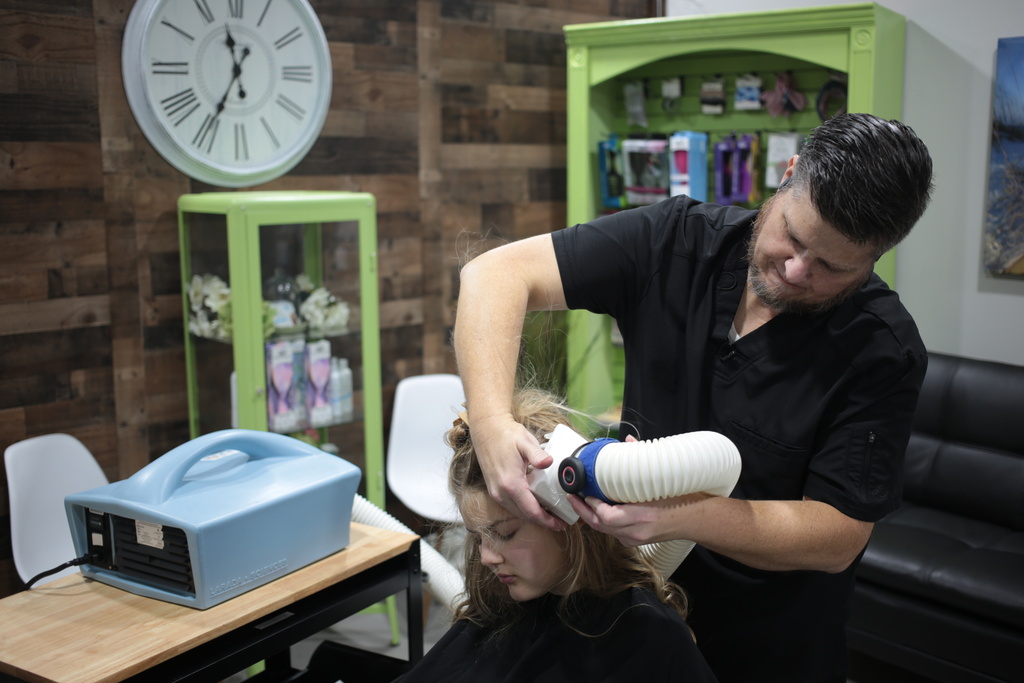 Jacob Anthon demonstrates the use of an FDA-cleared device that uses a combination of airflow temperature, speed, and direction to kill lice and eggs at Lice Clinics of America in Sugar Land, Texas, Monday, Sept. 22, 2025. (AP Photo/Lekan Oyekanmi)