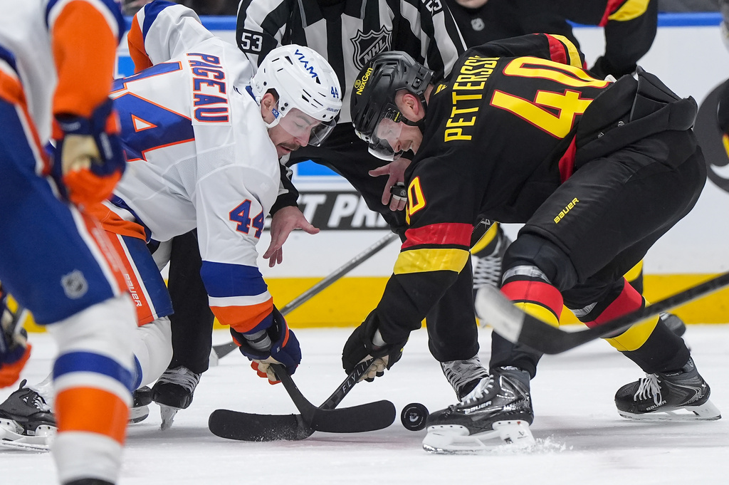 Vancouver Canucks' Elias Pettersson (40) wins a faceoff against New York Islanders' Jean-Gabriel Pageau (44) during the third period of an NHL hockey game in Vancouver, B.C., Monday, Jan. 19, 2026. (Darryl Dyck/The Canadian Press via AP)