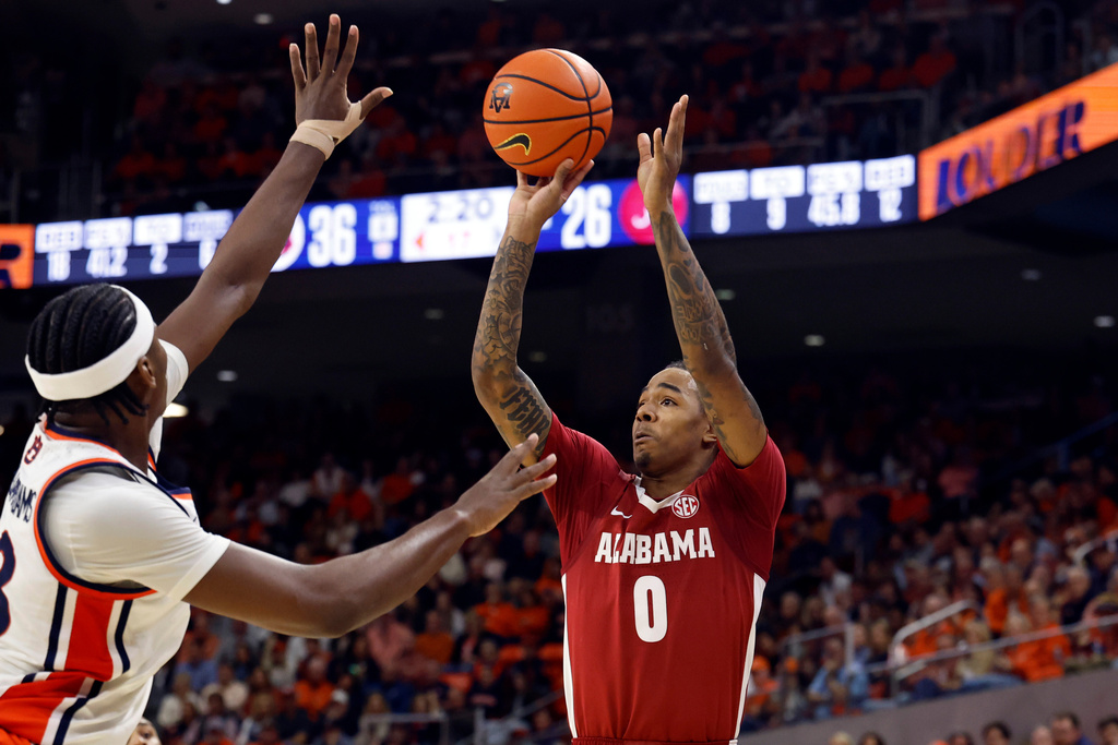 Alabama guard Labaron Philon (0) shoots a three-pointer as Auburn guard CJ Williams (13) defends during the first half of an NCAA college basketball game Saturday, Feb. 7, 2026, in Auburn, Ala. (AP Photo/Butch Dill)